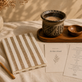 Rumah Ritual Kit med håndlaget keramikkopp fra Bali, serveringsbrett i tre, stoffinnbundet journal og ritualkort på lintekstil.